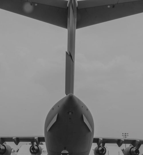 Black and white rear view of a large military aircraft on display outdoors.